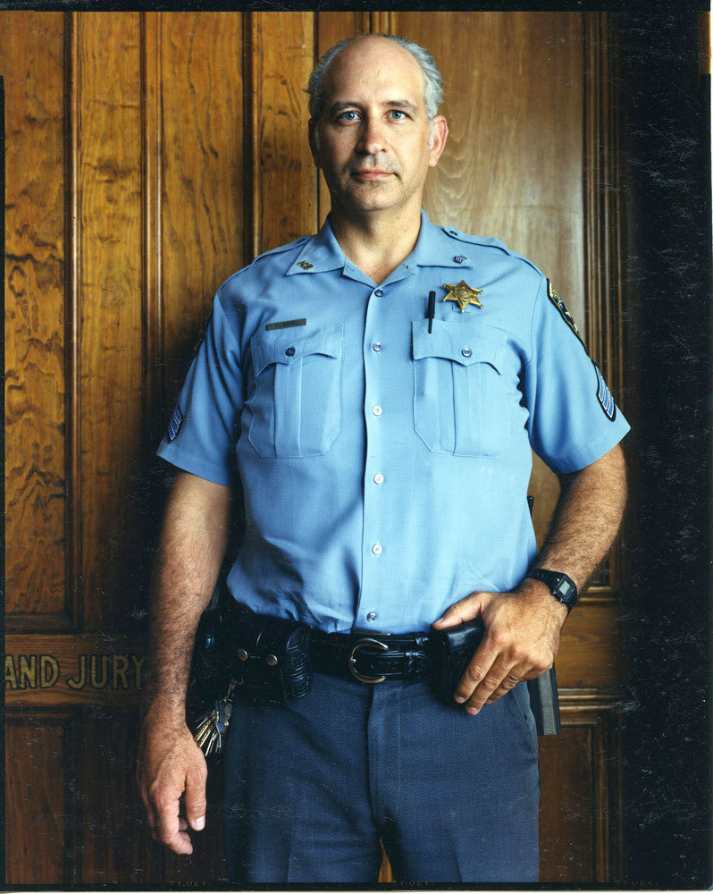 Court officer in blue uniform, in front of Grand Jury door